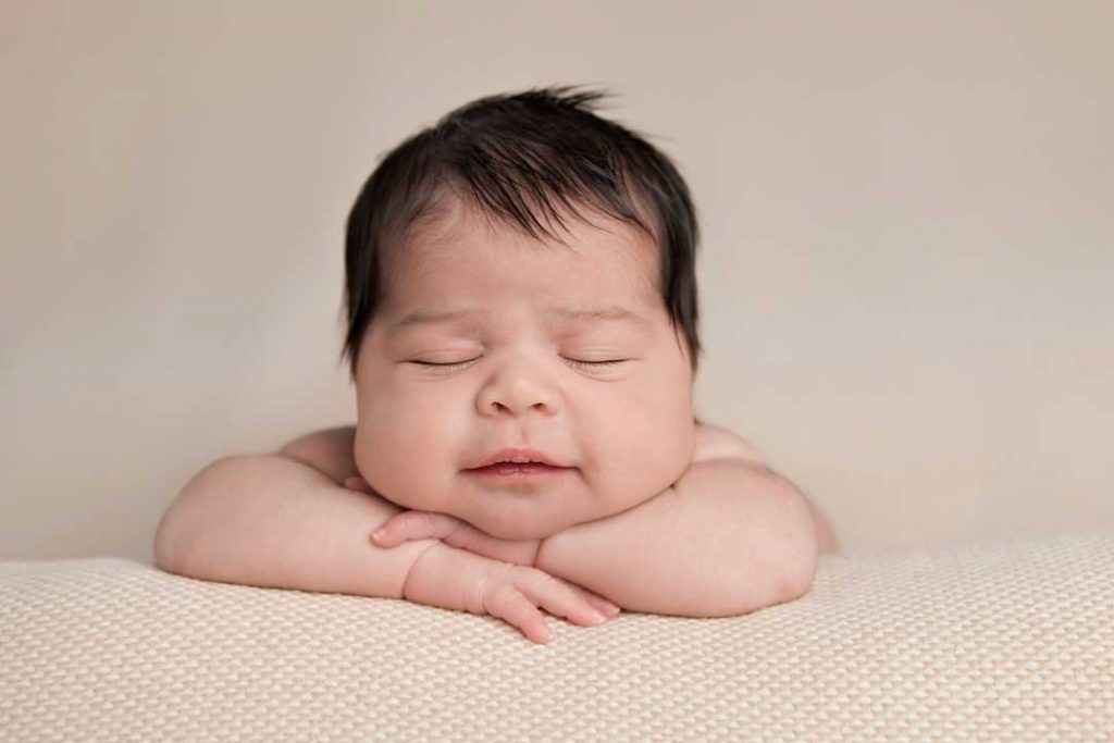 Newborn sleeping on arms.