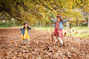 two girls playing in Autumn leaves
