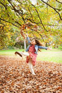 Girl Kiching Autumn Leaves