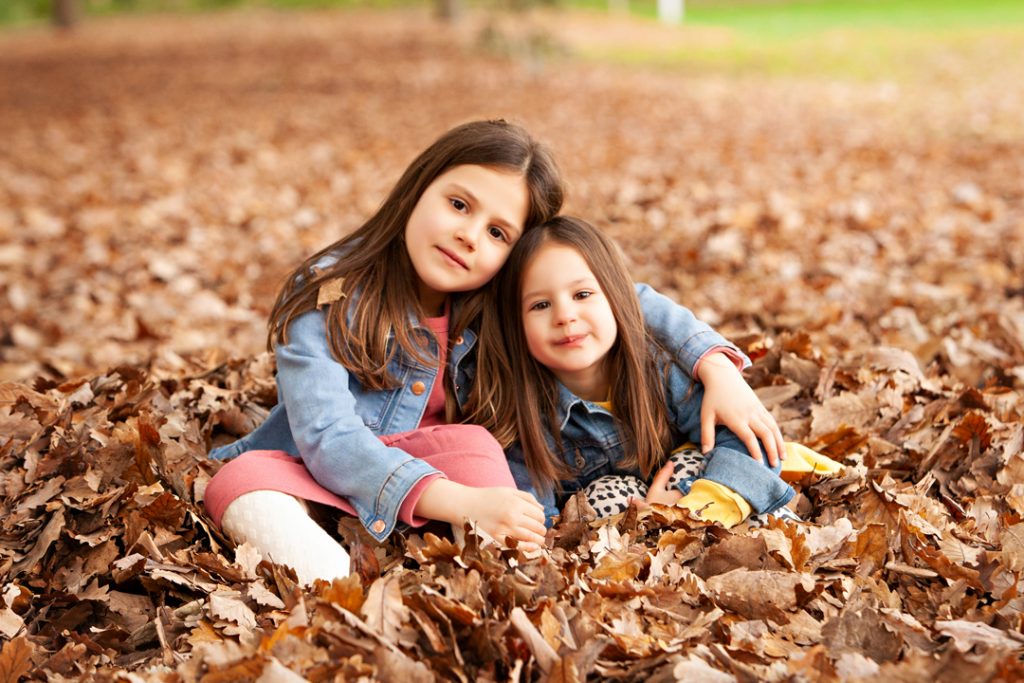 two girls hugging in Autumn leaves in Macedon Ranges