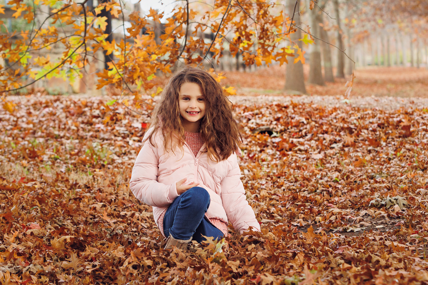 girl sitting in autumn leaves