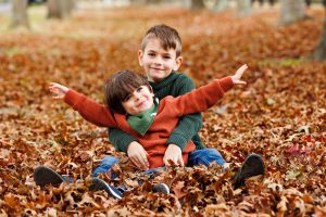 two boys in autumn leaves