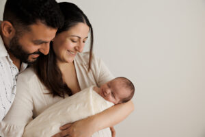 newborn parents and baby smiling at their newborn daughter, In-Home Newborn Photography in Aintree