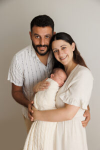 newborn parents and baby smiling at the camera, In-Home Newborn Photography in Aintree