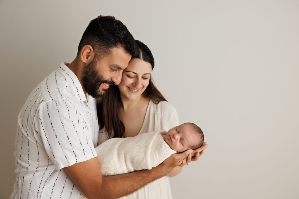 newborn parents and baby smiling at their newborn daughter, In-Home Newborn Photography in Aintree