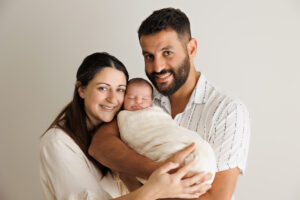 newborn parents and baby smiling at the camera, In-Home Newborn Photography in Aintree
