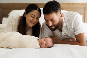 parents and newborn baby laying on bed, In-Home Newborn Photography in Aintree