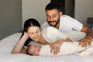 parents and newborn baby laying on bed, In-Home Newborn Photography in Aintree