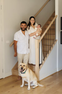 parents and newborn and family dog standing in stairwell